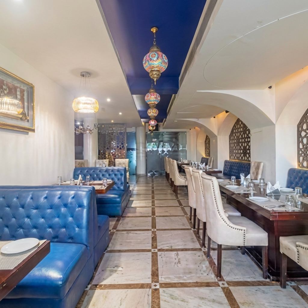 Air-conditioned dining hall at Pankhuri with blue booth seating, family tables, arches and hanging lamps